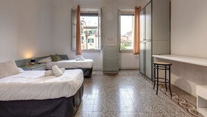 Een compacte hotelkamer met twee bedden, een kitchenette en uitzicht op de stad.