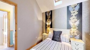 Een slaapkamer met een bed, nachtkastjes, een lamp en een muur met decoratief ontwerp.