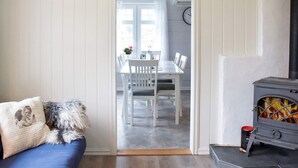 Una stanza accogliente con un divano blu, un animale domestico, un camino e un'area pranzo visibile attraverso una porta aperta.