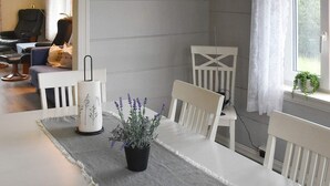 Un'area pranzo con un tavolo bianco, un sottopiattino grigio e una pianta di lavanda in vaso.