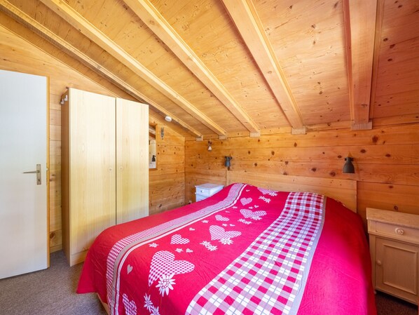A wooden cabin bedroom with a bed, a wardrobe, and a door. - Chalet in Fiesch Near Aletsch Glacier (Fiesch)