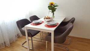 Ein Esstisch mit vier Stühlen, einer Vase mit einer Sonnenblume und einem Brotkorb.