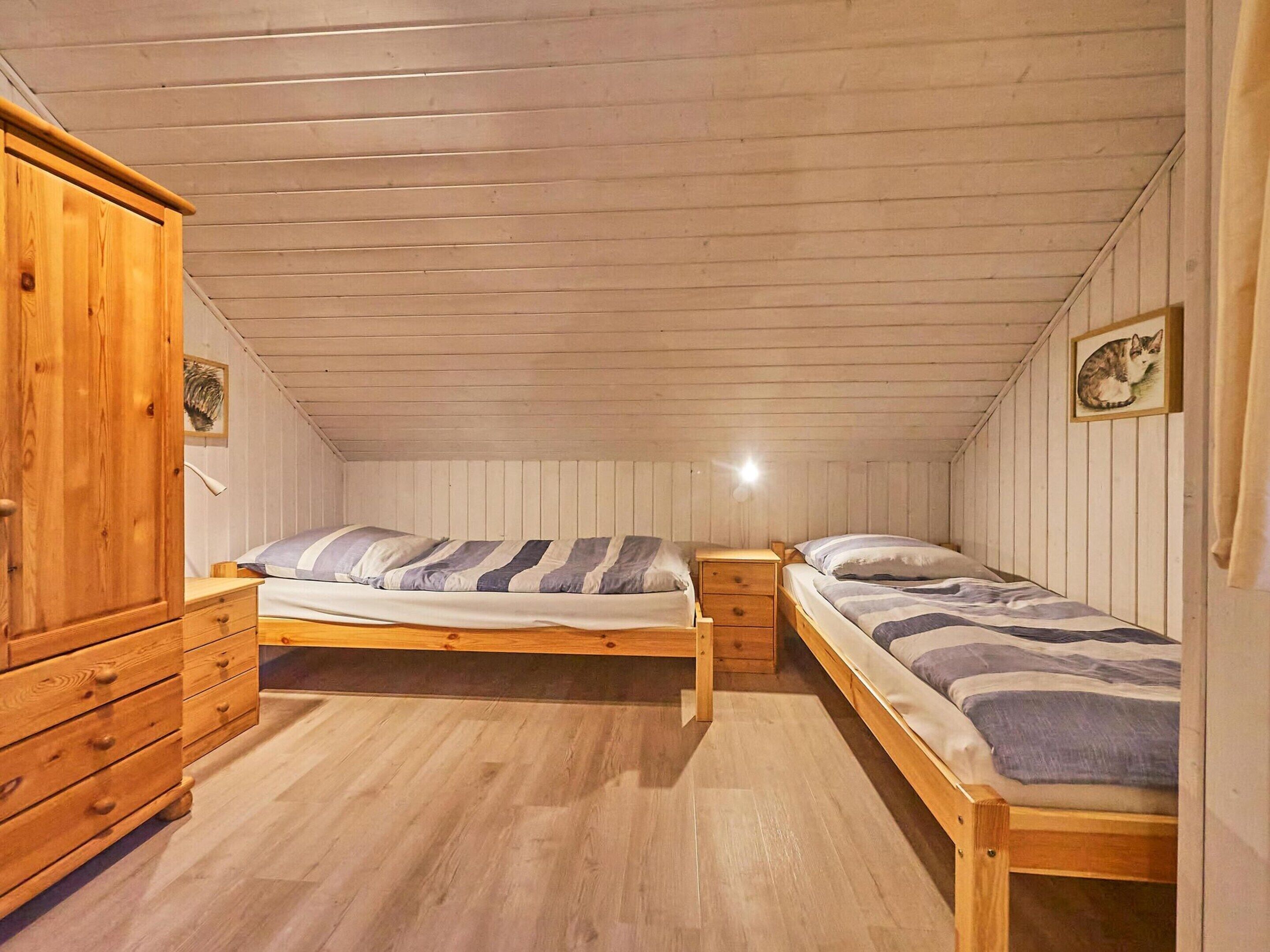 Een kleine, gezellige kamer met twee houten bedden, een houten kast en een klein nachtkastje.