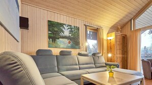 Ein modernes Wohnzimmer mit einem Ecksofa, einem Couchtisch und einem Gemälde einer Flusslandschaft.