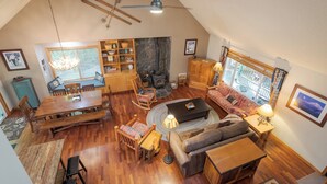 A cozy loft-style living room with a dining area, fireplace, and large windows. - Summer special, stay before 9/8/26 get third night free. (Welches)
