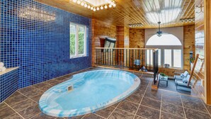 Een houten cabin met een bubbelbad, betegelde muren en een balkon met uitzicht.