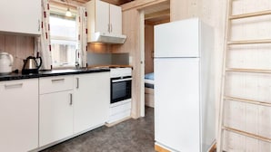 Una cocina compacta con gabinetes blancos, estufa, horno y refrigerador.