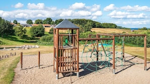 Een speeltuin met een houten klimconstructie en een klein prieeltje.