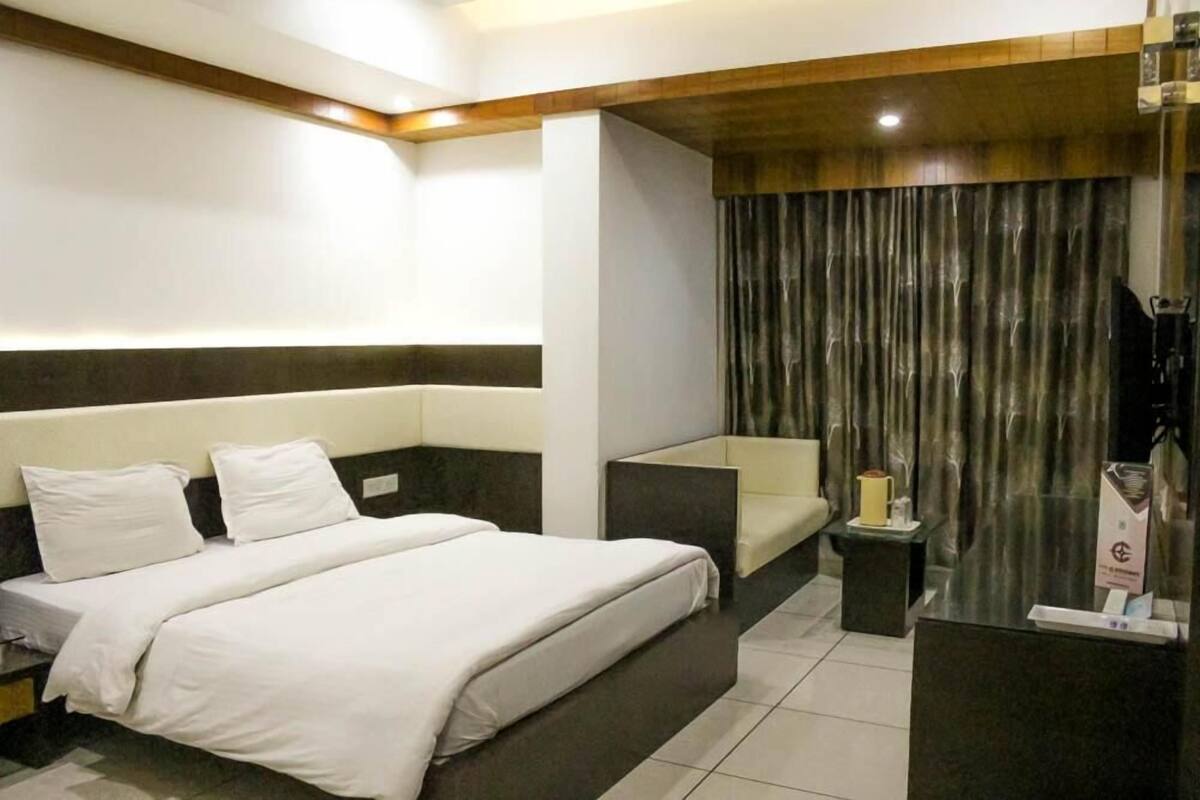 Una habitación de hotel moderna con una cama grande, un pequeño sofá, un escritorio y una cortina.