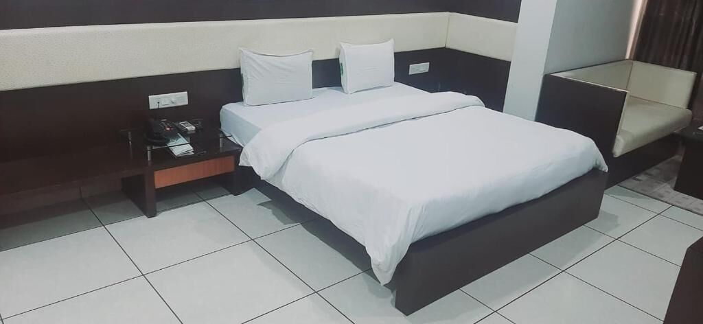 A hotel room with a bed, a nightstand, and a chair.