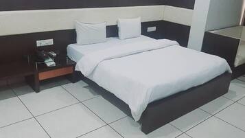 A hotel room with a bed, a nightstand, and a chair.