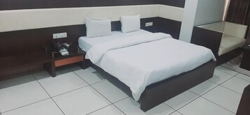 A hotel room with a bed, a nightstand, and a chair.