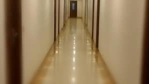 A long, narrow hallway with a shiny, reflective floor and walls. - Hotel Apex Inn (Vapi)