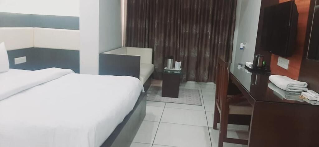 A hotel room with a bed, a small table, a TV, and a mirror.