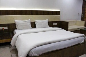 A neatly made bed with white linens, a wooden headboard, and a small bedside table with a lamp.