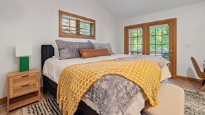 A bedroom with a bed, a nightstand, a chair, and a window. - 376 Disciples Village | Game Room | Fireplace | Walking Distance to Slopes! (Boyne Falls)