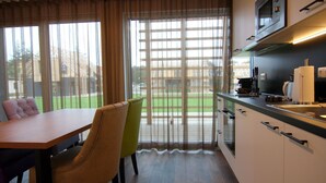 Una cocina moderna con comedor, ventanas amplias y vista a un espacio exterior verde.