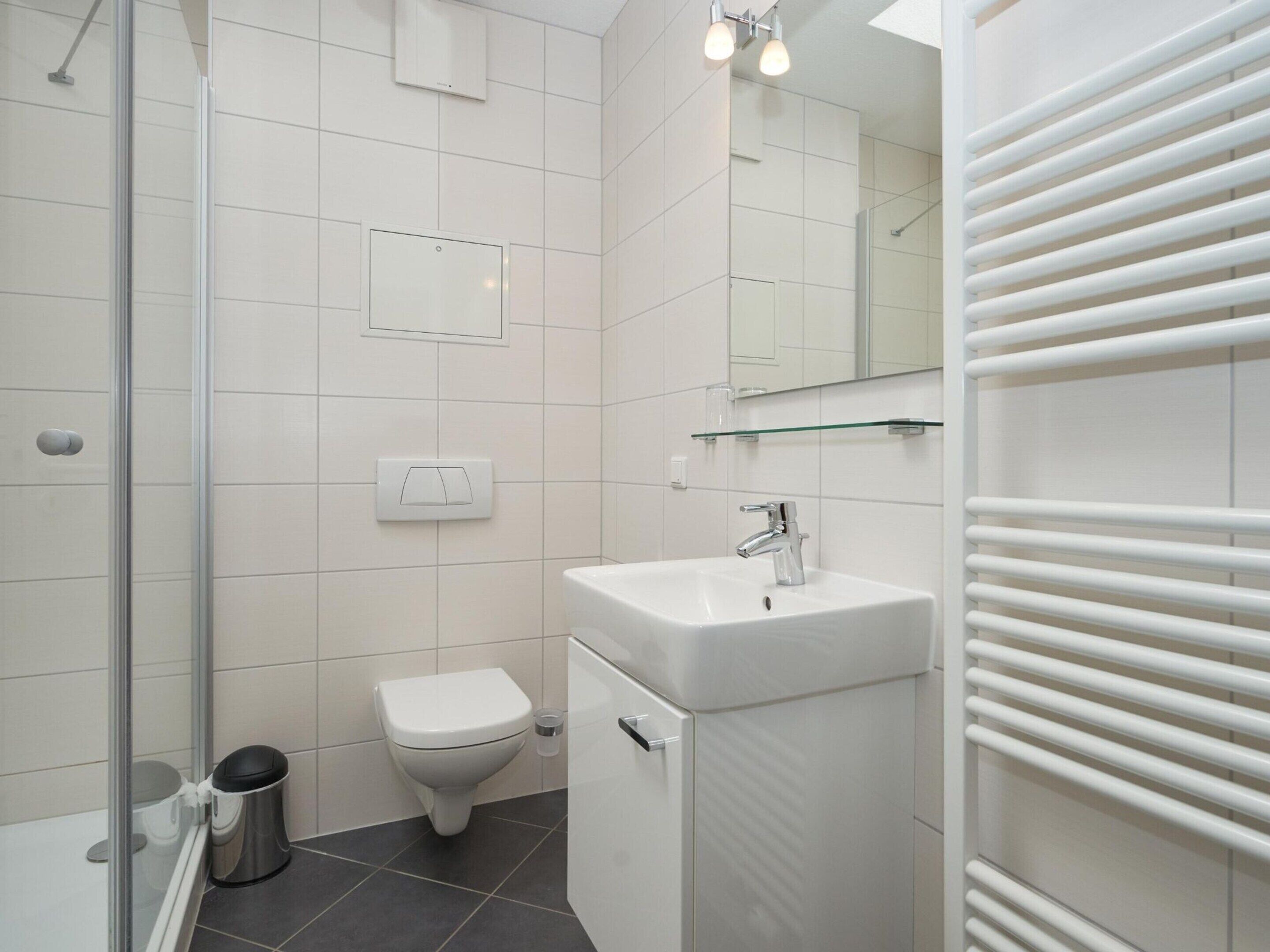 Une salle de bain moderne avec une douche à parois de verre, un lavabo blanc et des toilettes.