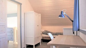 A bedroom with a wooden ceiling, a desk with a chair, a bed, and a wardrobe. - Skandinavisches Ferienhaus in Mirow (Mirow)