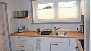 A compact kitchen with a wooden countertop, a double sink, a microwave, and a toaster. - Skandinavisches Ferienhaus in Mirow (Mirow)
