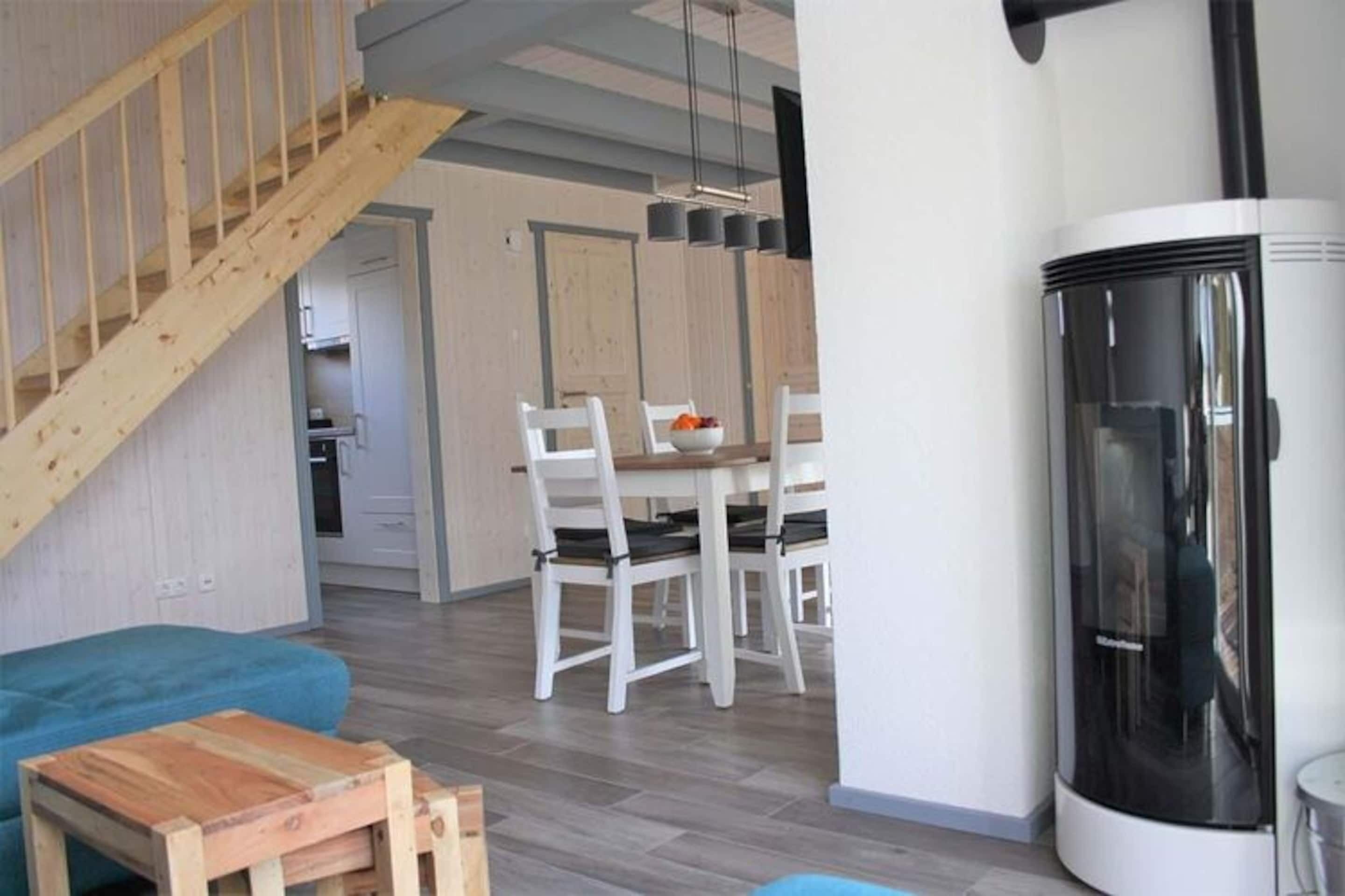 A modern living room with a staircase, a dining area, and a fireplace.