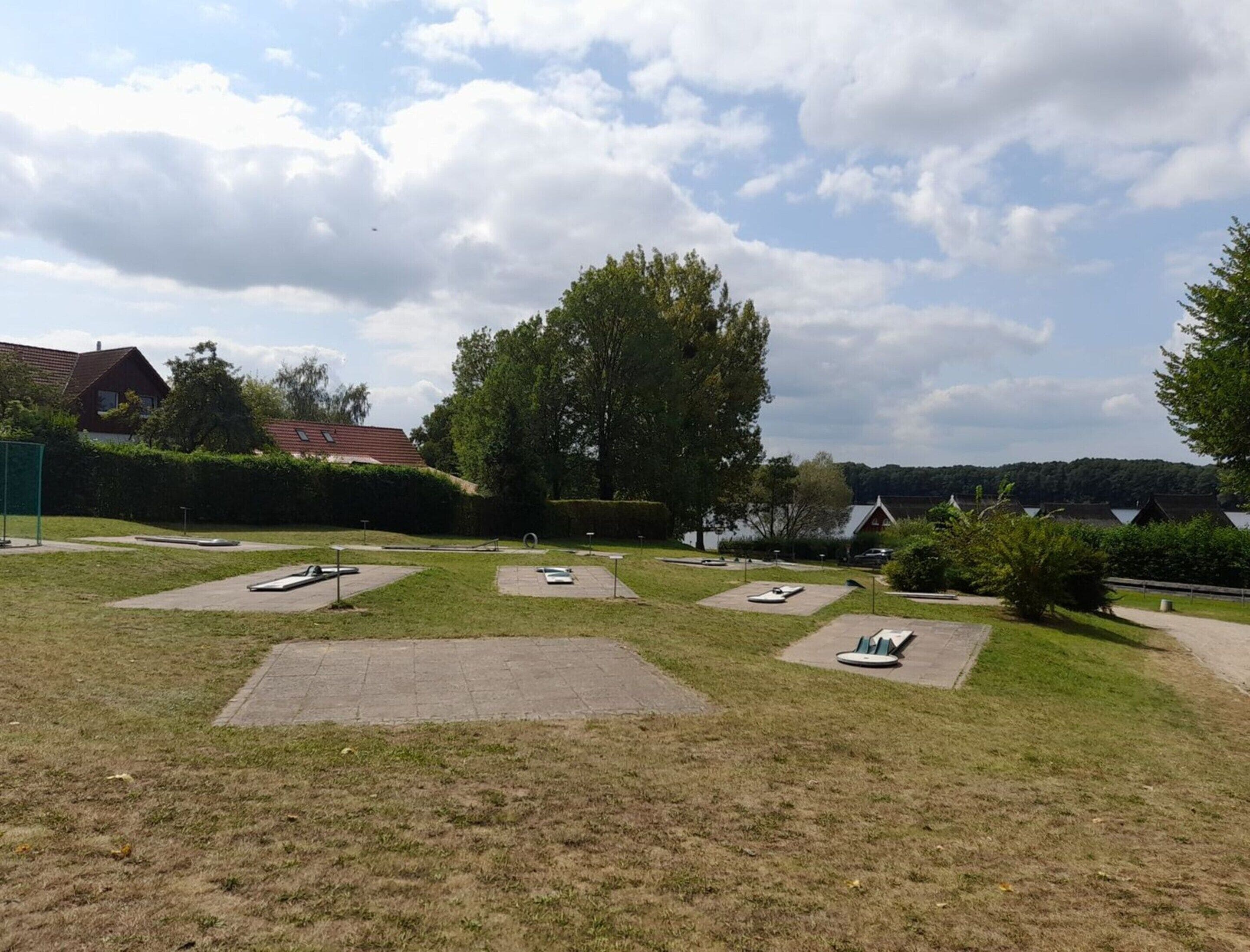 A grassy area with several circular seating areas and a large tree in the center.