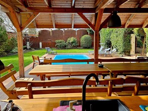 Relax by the pool table in a serene outdoor space with seating and a pergola overhead.