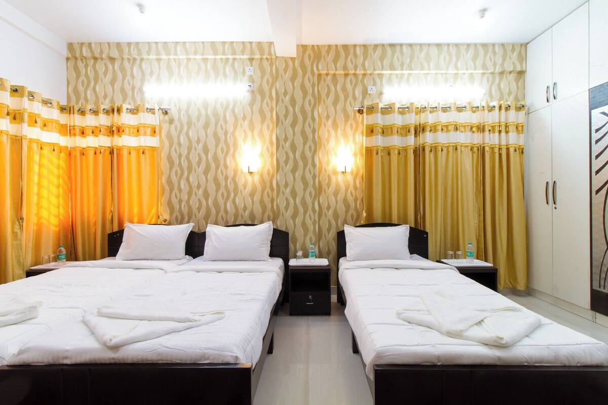 A hotel room with two beds, a wardrobe, and a bathroom.