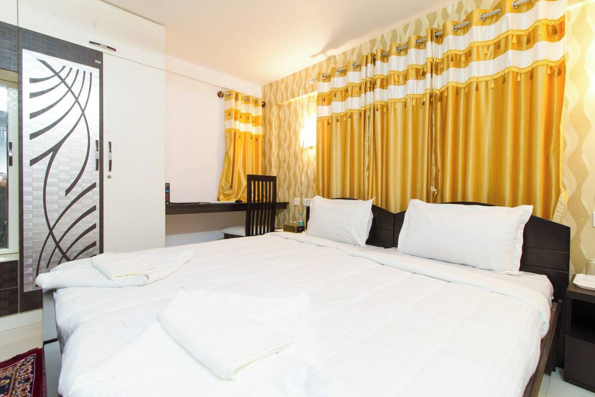 A hotel room with a large bed, a desk, and a chair.