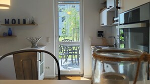 Eine moderne Küche mit Essbereich und Blick auf Grünflächen, mit einem Glas auf dem Tisch.