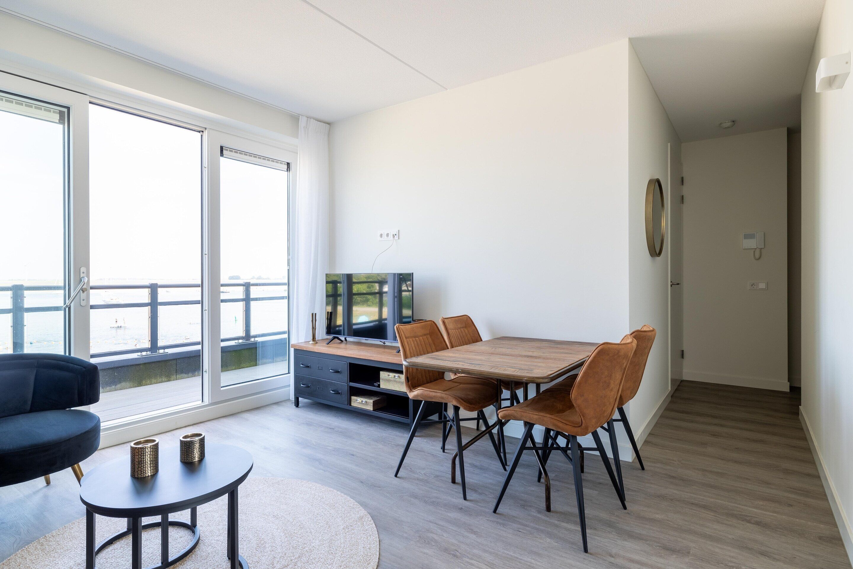 A modern living room with a dining table, chairs, a sofa, and a TV.