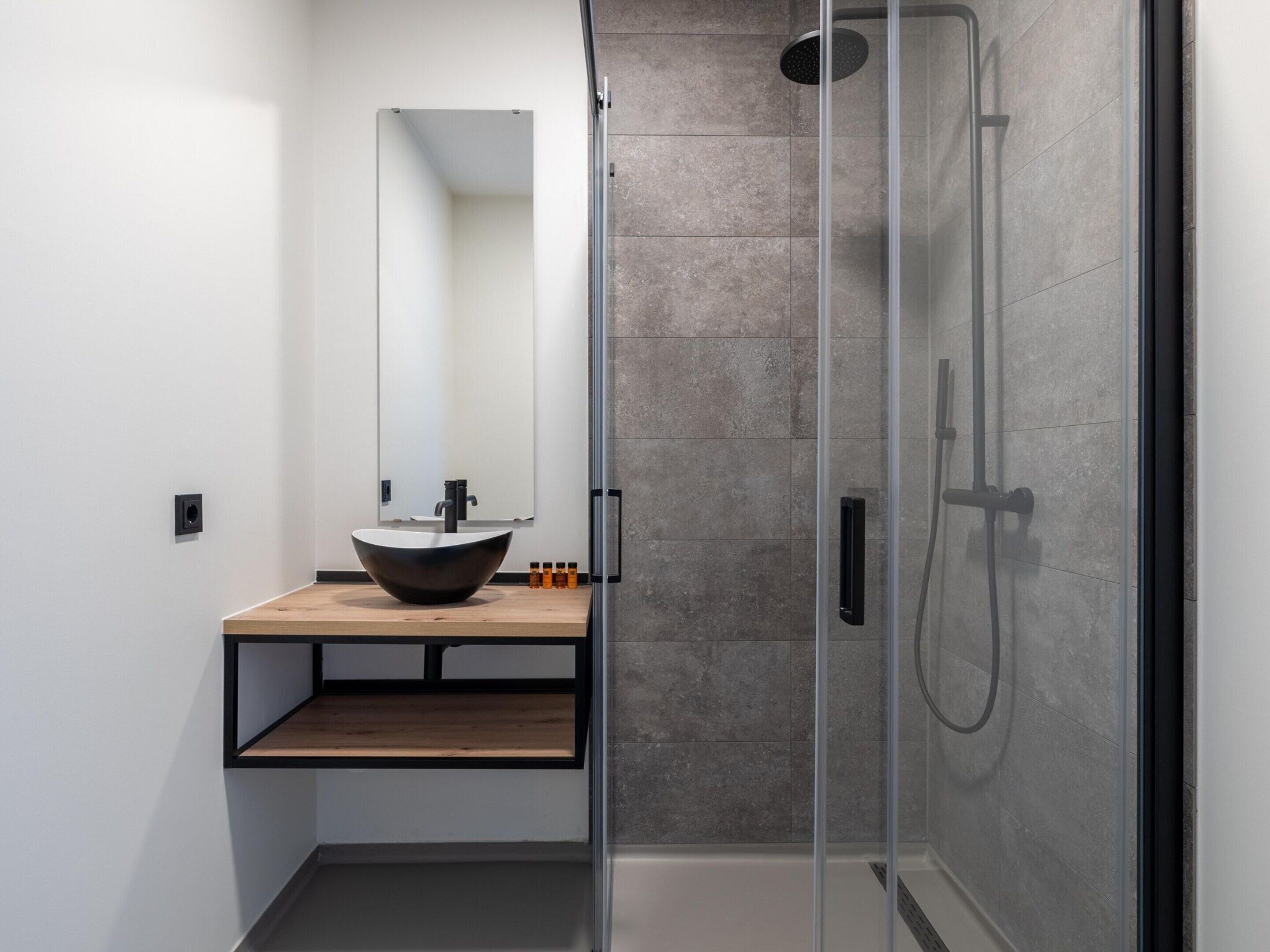 Een moderne badkamer met een grote spiegel, een wastafel en een douche met glazen wanden.