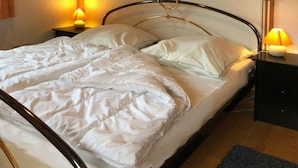 Un lit bien fait, avec du linge de lit blanc, deux lampes de chevet et une table de nuit noire.