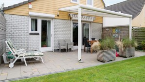 Una casa con un patio, una zona de estar cubierta y un muro de ladrillo.