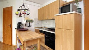 Una cocina compacta con armarios de madera, microondas y lavavajillas.