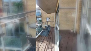 A balcony with a wooden floor, a table, and chairs.