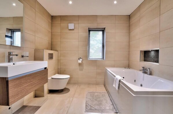 A modern bathroom with a bathtub, toilet, and sink.