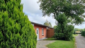 A residential property with a paved driveway, a red house, and well-maintained green lawns. - Reihenhaus am Gross Labenzer See, Klein Labenz (Warin)