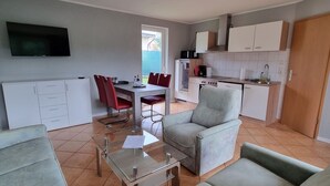 A modern living room with a glass coffee table, a sofa, and a dining area with red chairs. - Reihenhaus am Gross Labenzer See, Klein Labenz (Warin)