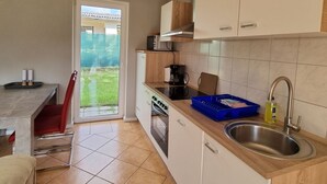 A modern kitchen with white cabinets, a stainless steel sink, and a sliding glass door leading to a patio. - Reihenhaus am Gross Labenzer See, Klein Labenz (Warin)
