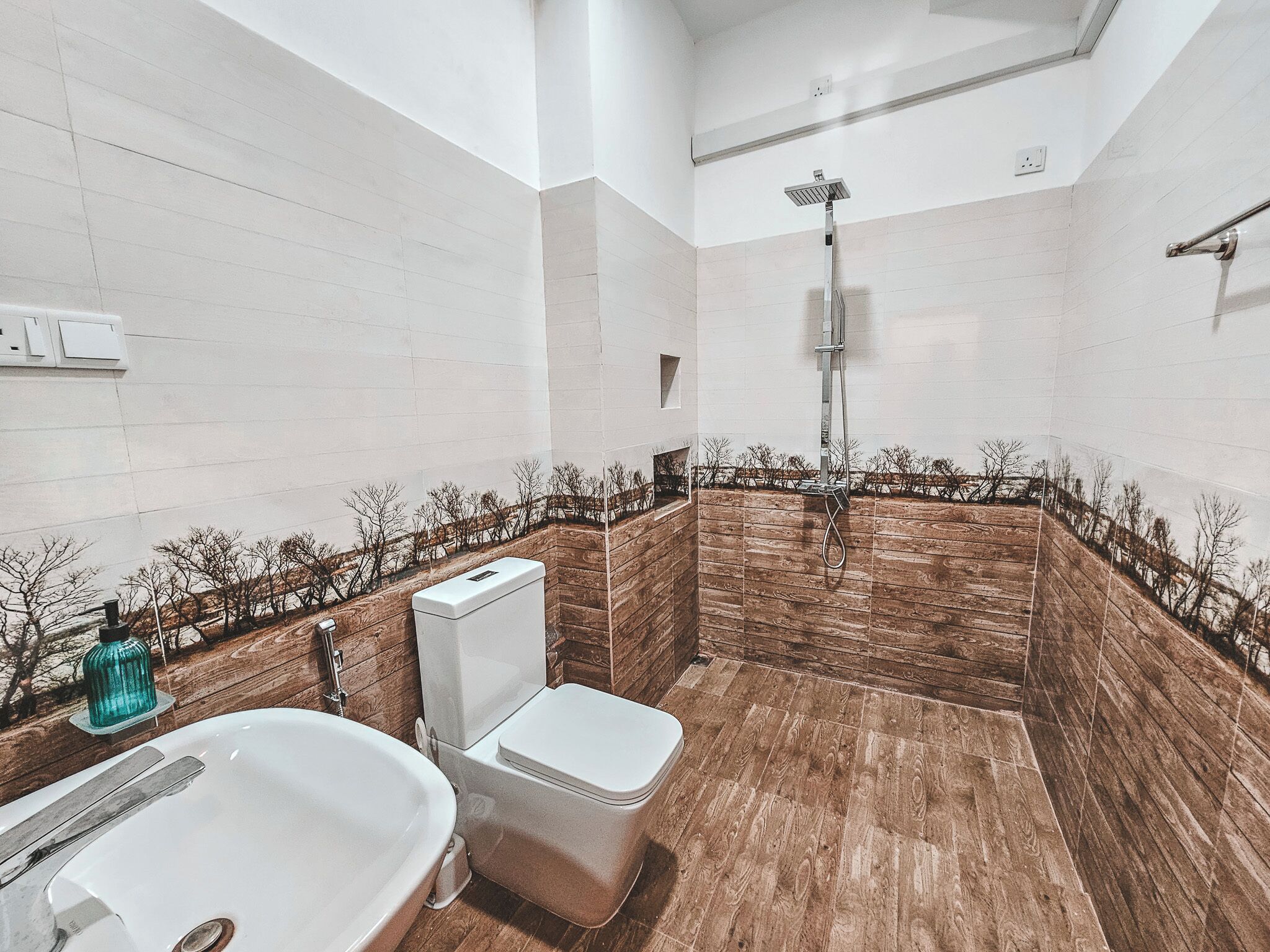 A bathroom with a wooden vanity, a white sink, a toilet, and a shower.