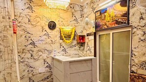 A room with a marble wall, a reception desk, a red sofa, and a wooden bed. - Maya Inn Paying Guest House By GRB (Varanasi)