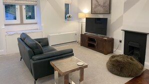 Una sala de estar moderna con sofá, televisor, chimenea y una pequeña mesa.