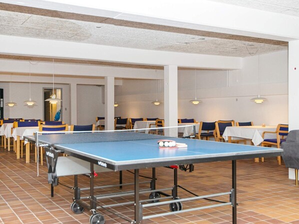 A ping pong table in a dining area with chairs and tables.