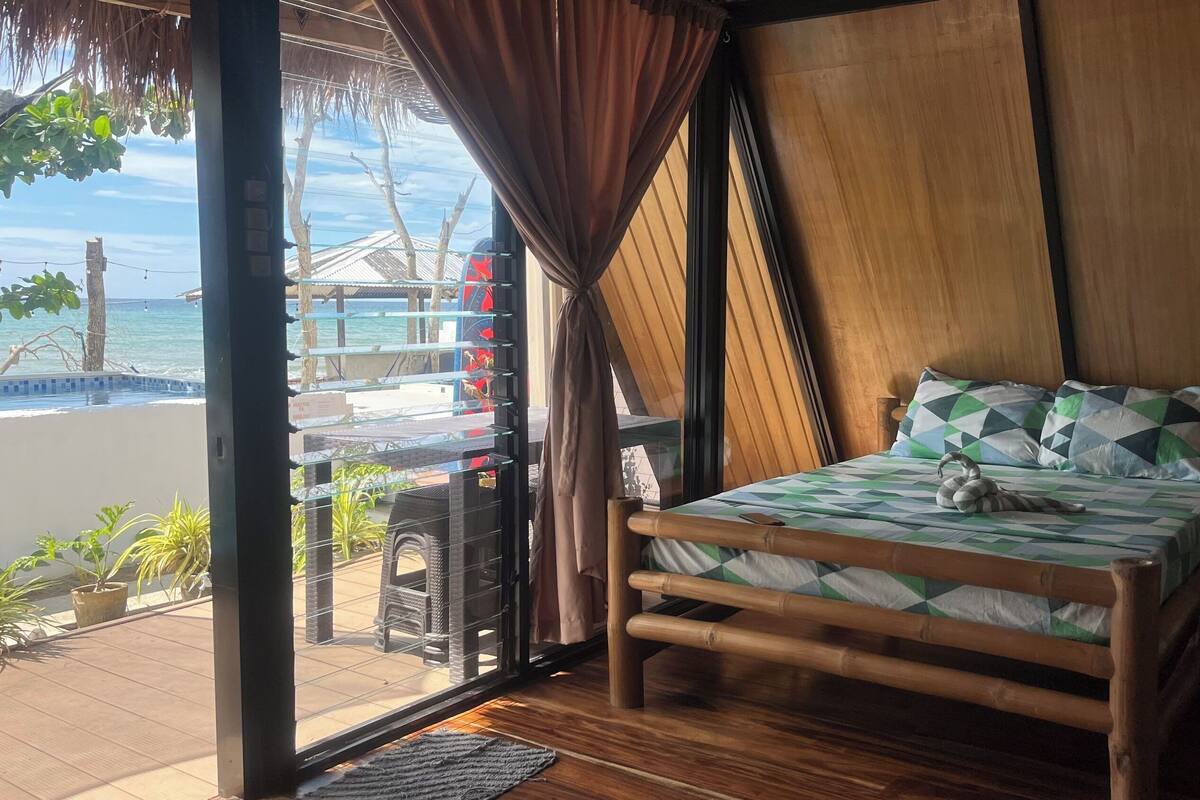 Una habitación con cama, suelo de madera y vistas a la playa y al océano.