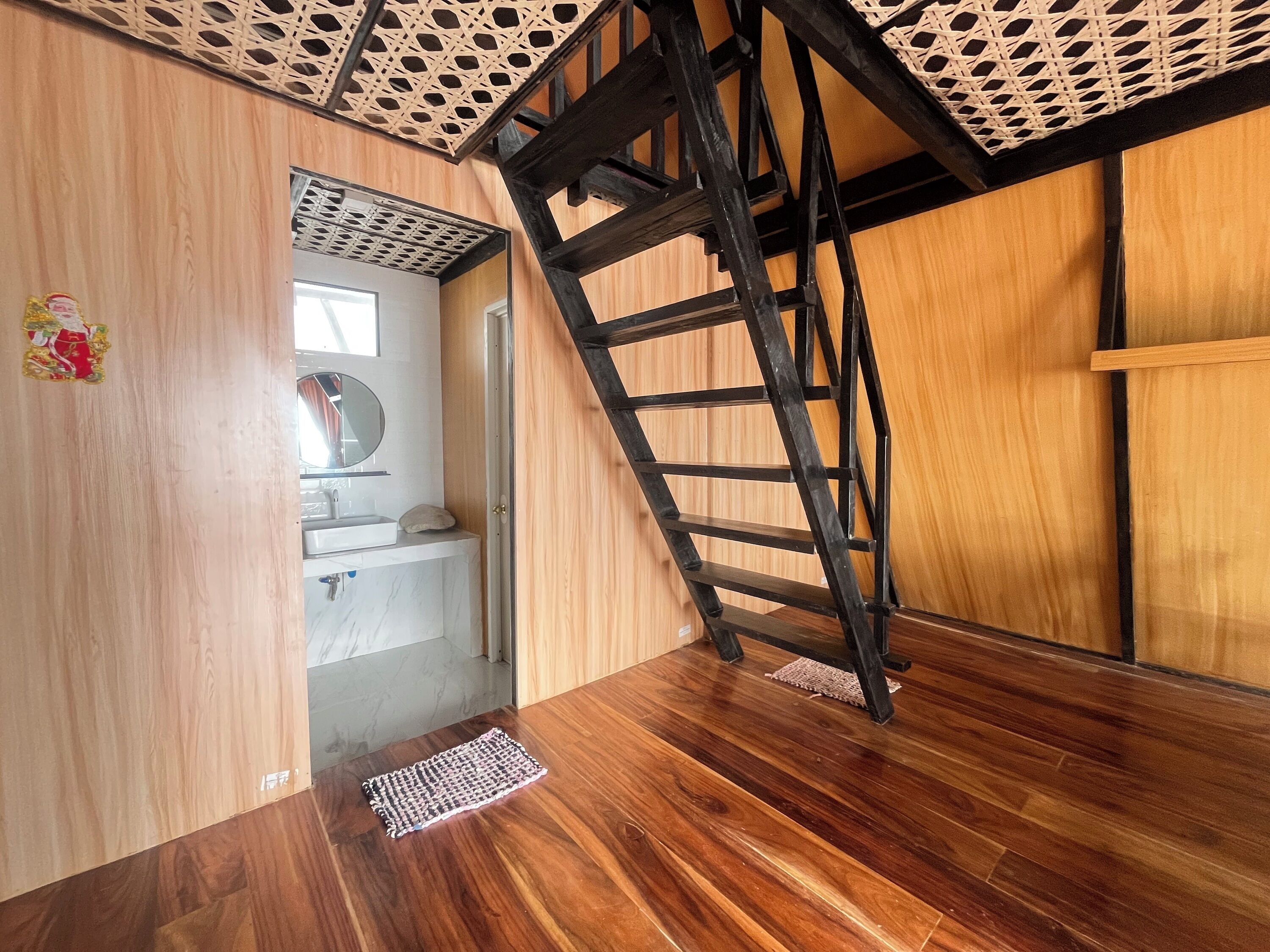 A wooden interior with a staircase, a small bathroom, and a wooden floor.