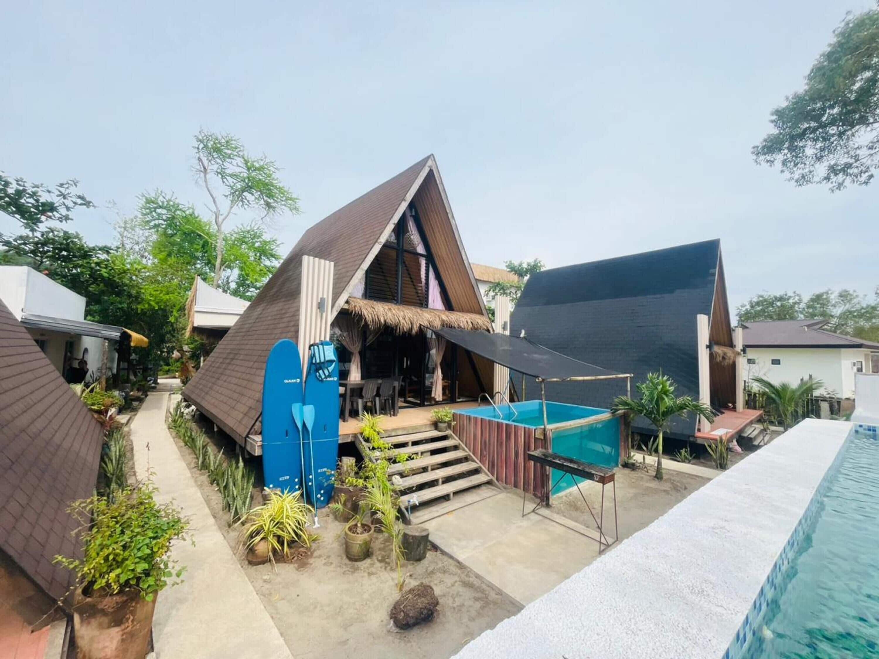 A modern bungalow with a thatched roof, a swimming pool, and a covered outdoor seating area.