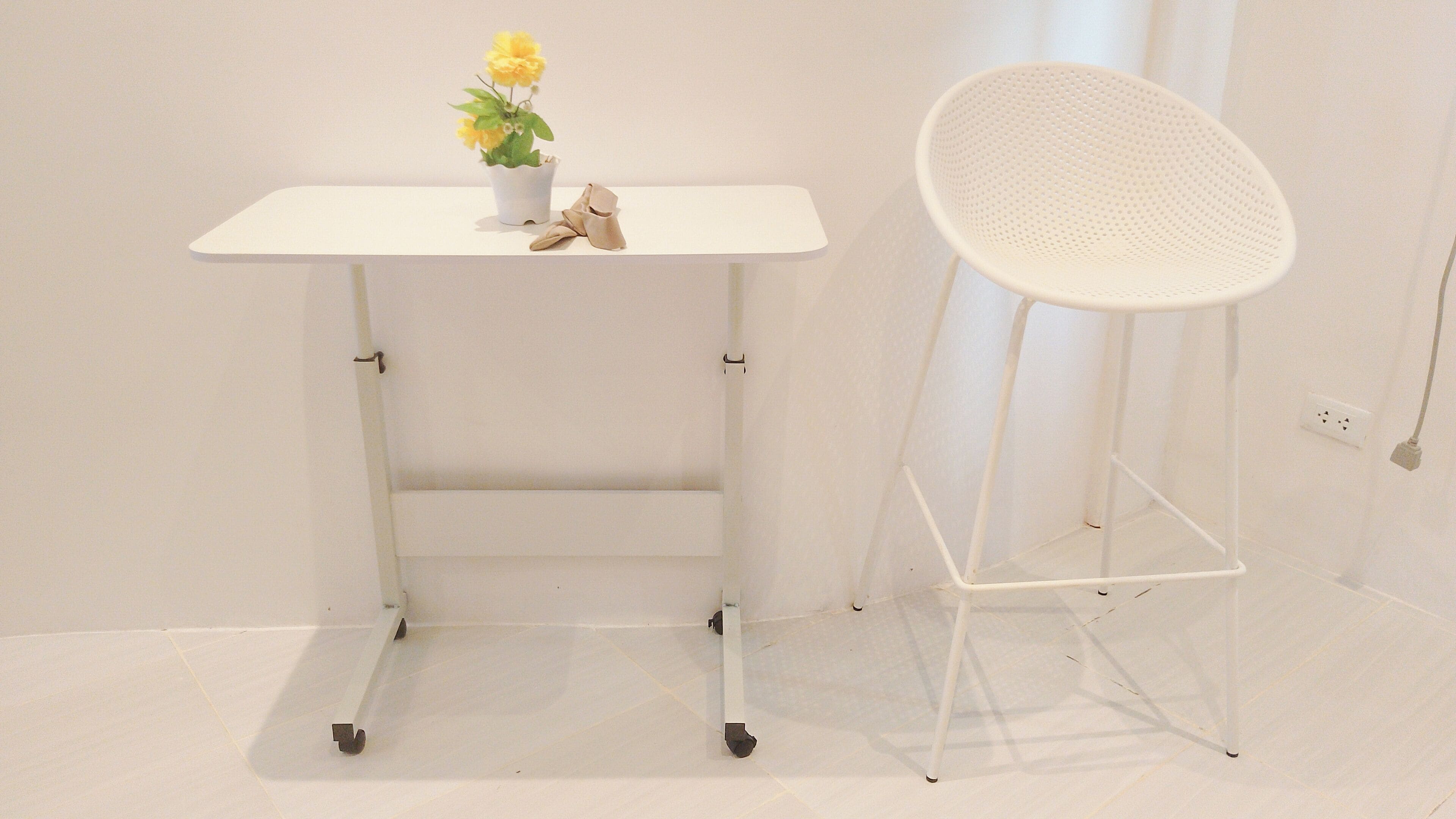 A white desk with a potted plant and a white chair.