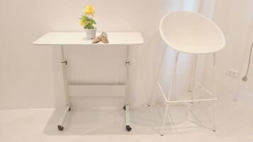 A white desk with a potted plant and a white chair.