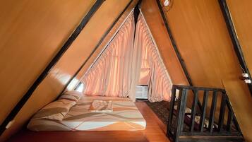 Un rincón acogedor, triangular, con una cama, una mesita y una silla.